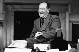 CS Lewis, who carried on a Latin correspondence, sitting at a desk smiling